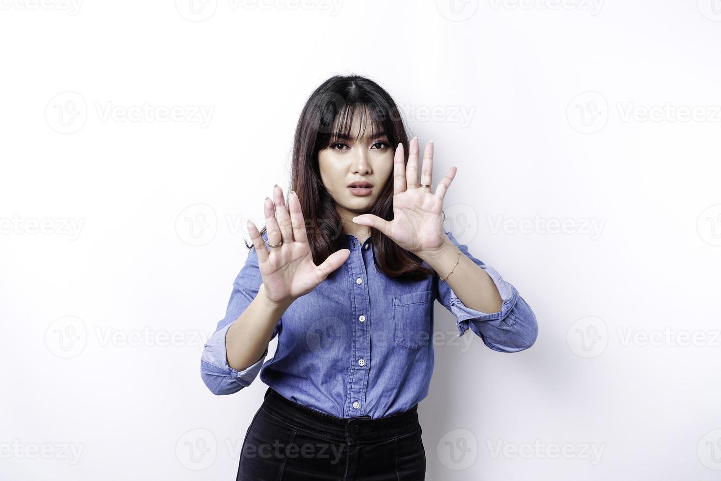jovem mulher asiática isolada no fundo branco, parece deprimida, rosto coberto por dedos assustados e nervosos. foto