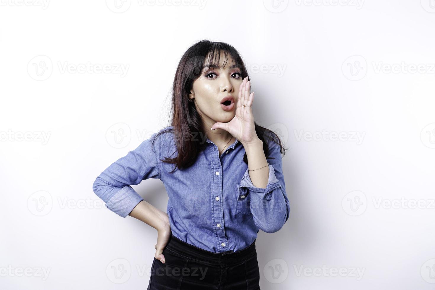 jovem mulher bonita vestindo uma camisa azul gritando e gritando alto com a mão na boca. conceito de comunicação. foto
