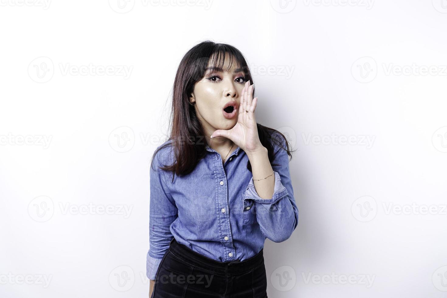 jovem mulher bonita vestindo uma camisa azul gritando e gritando alto com a mão na boca. conceito de comunicação. foto