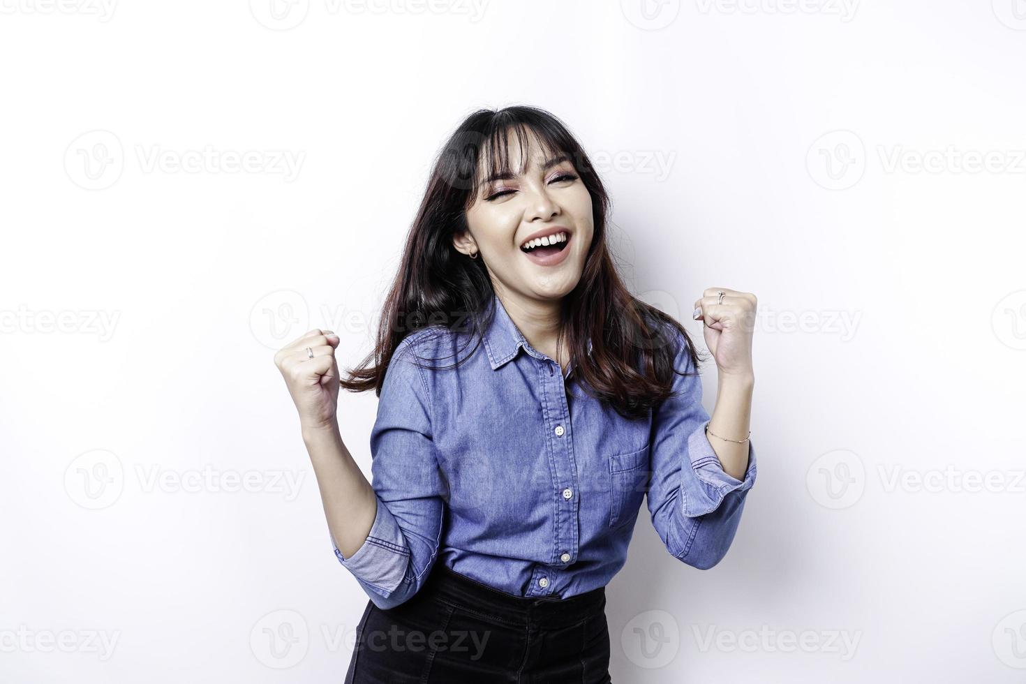 uma jovem mulher asiática com uma expressão de sucesso feliz vestindo camisa azul isolada por fundo branco foto