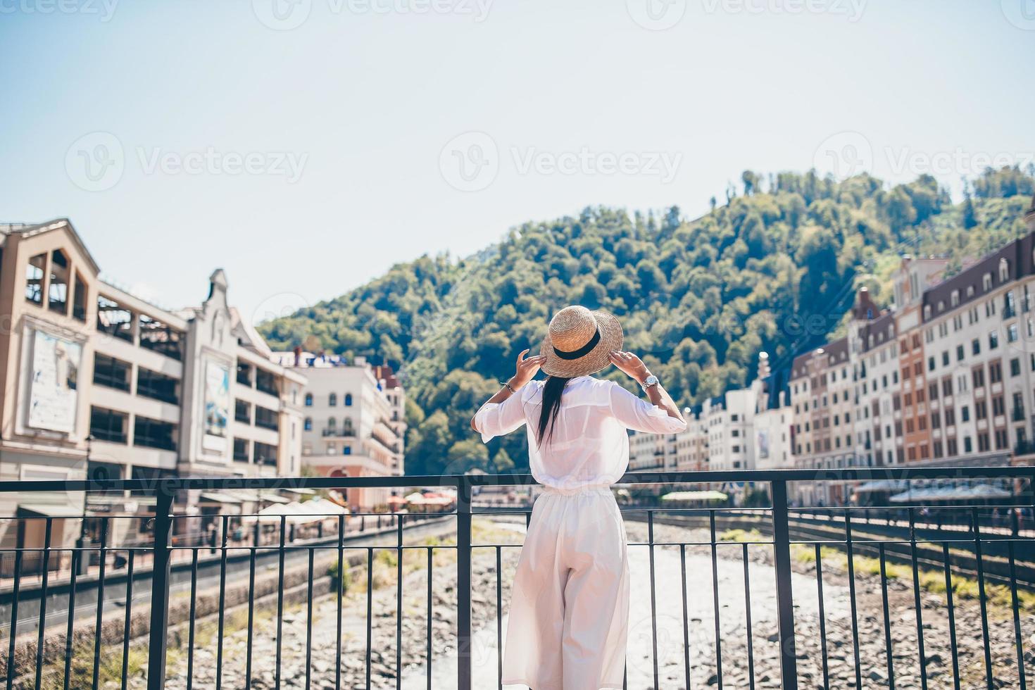 garota feliz no chapéu na margem de um rio de montanha em uma cidade europeia. foto