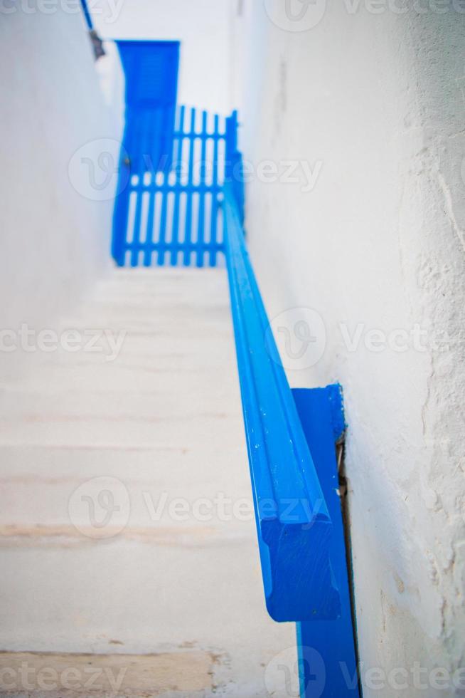 casas tradicionais com porta azul e escadas brancas nas ruas estreitas de mykonos, grécia. foto
