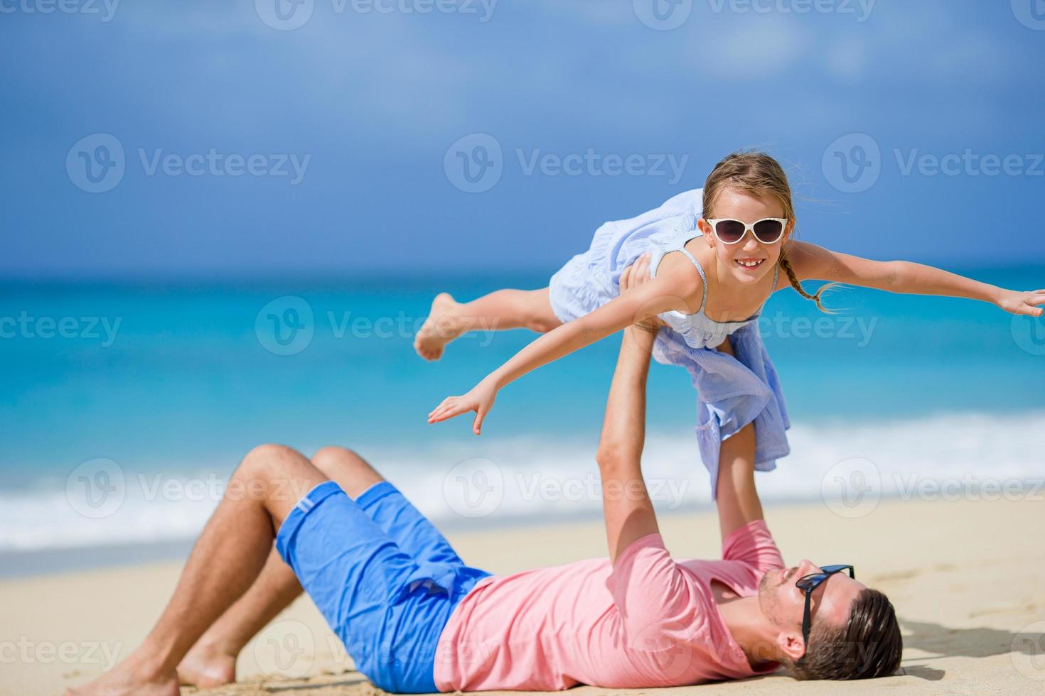 menina e pai feliz se divertindo durante as férias na praia foto