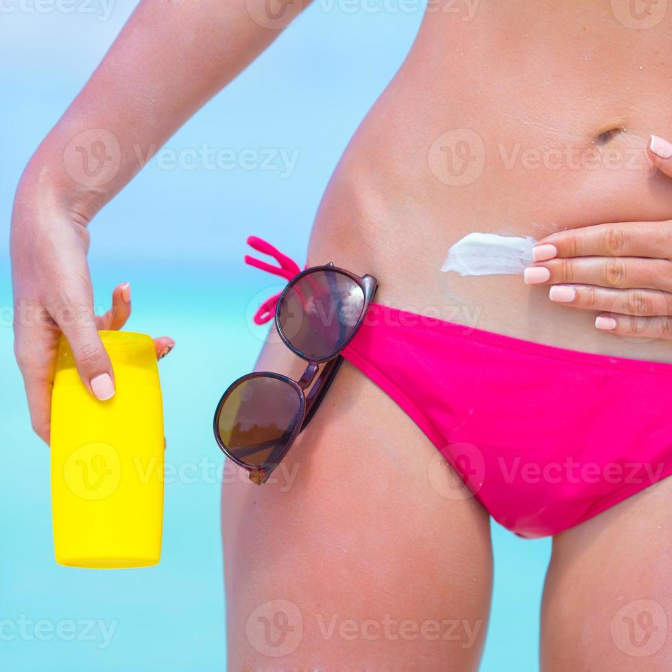 jovem aplicando protetor solar na praia branca foto