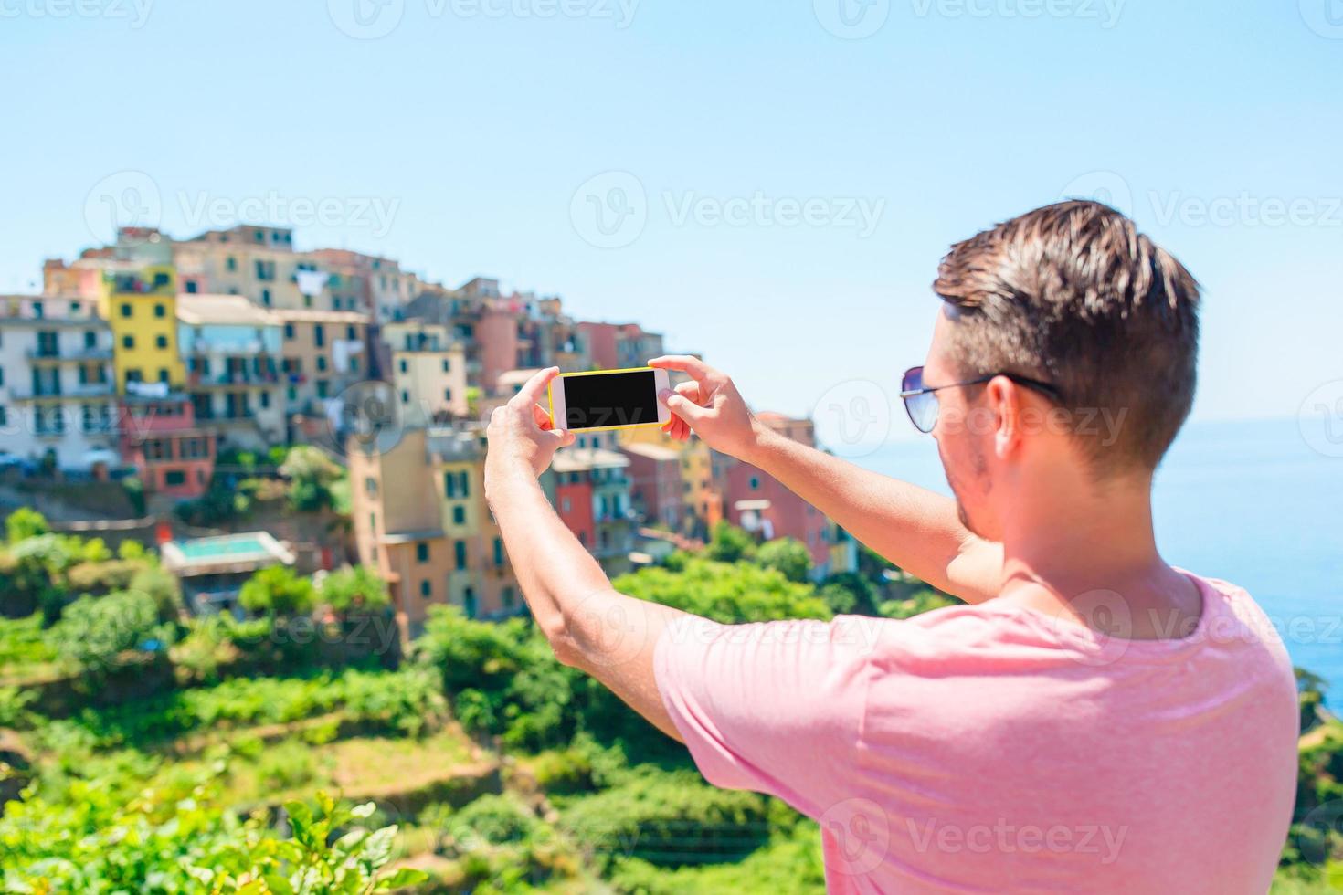 jovem tirando selfie fundo bela vila italiana antiga, cinque terre, ligúria, itália foto