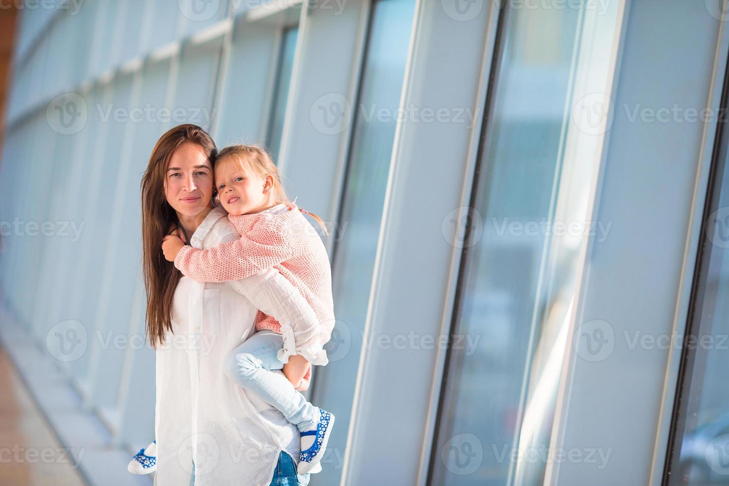 família feliz no aeroporto sentado na mala com cartão de embarque à espera de embarque foto