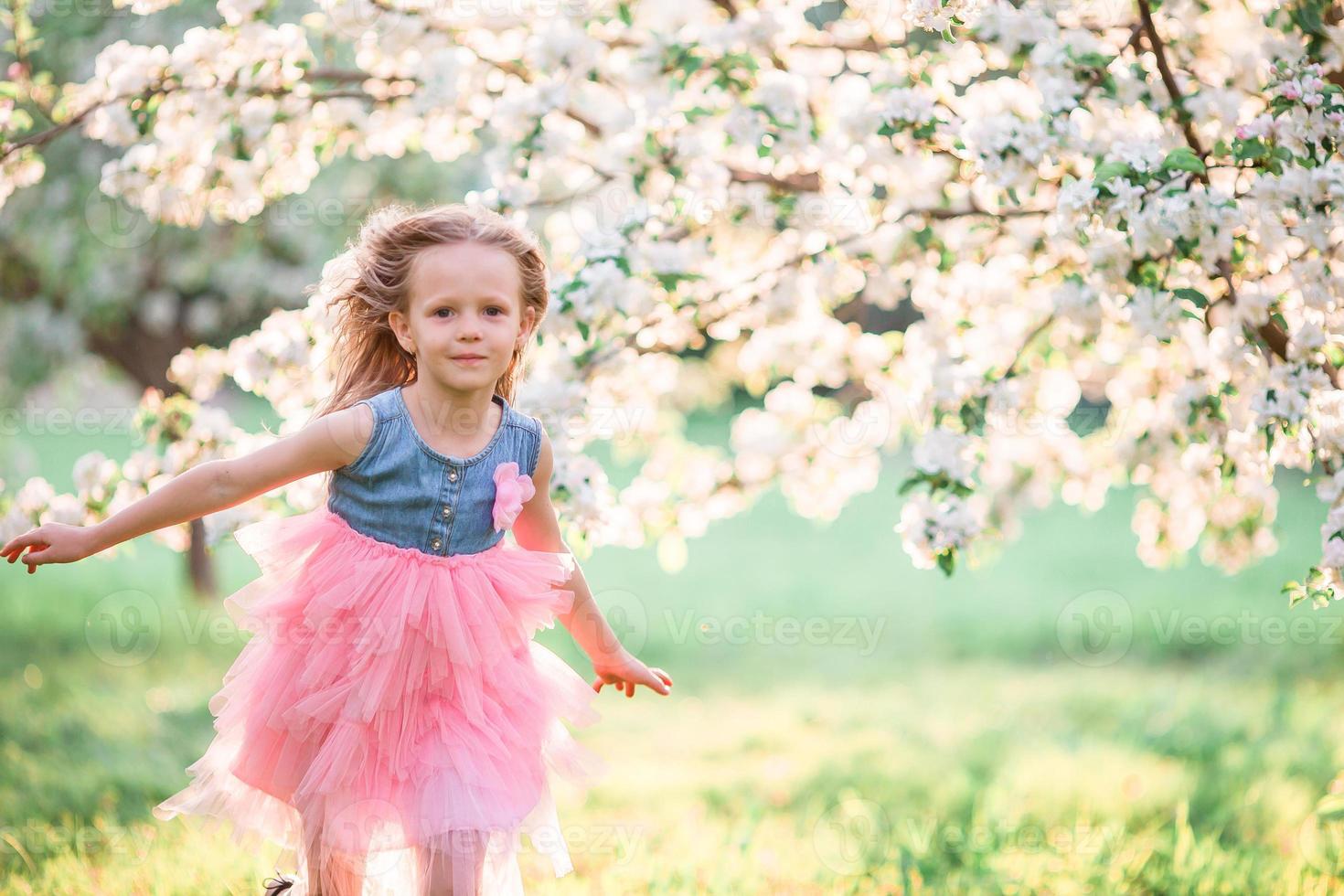 adorável menina aproveitando o dia de primavera no jardim de florescência de maçã foto