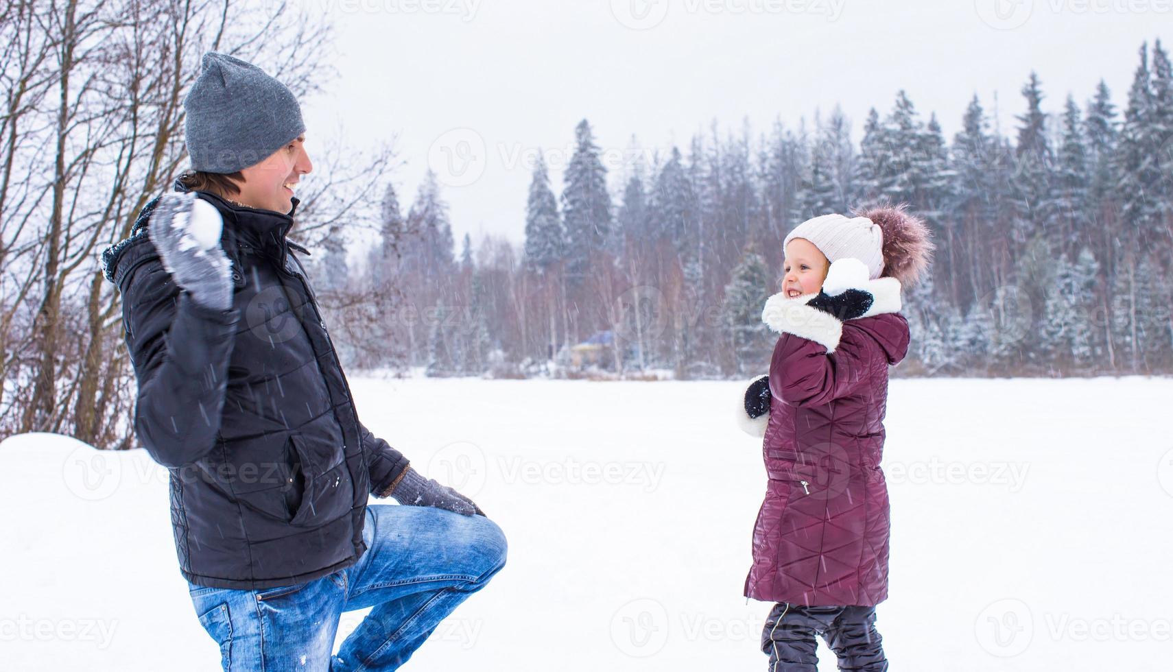 feliz pai e filha jogando bolas de neve em dia de neve de inverno foto