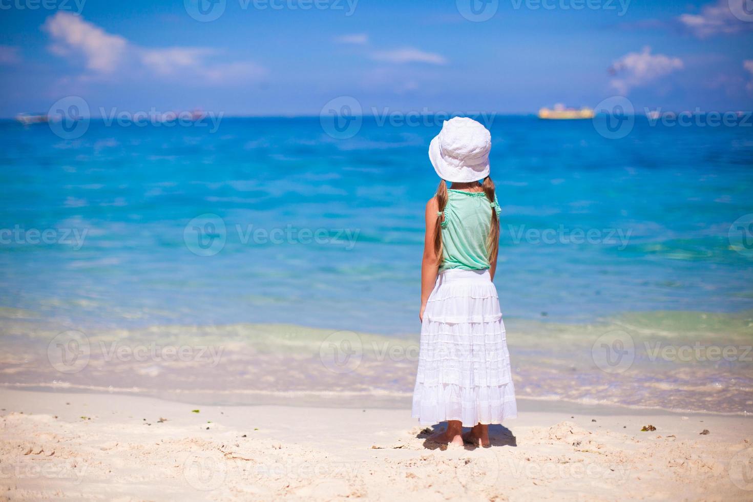 adorável garotinha caminhando na praia tropical branca foto