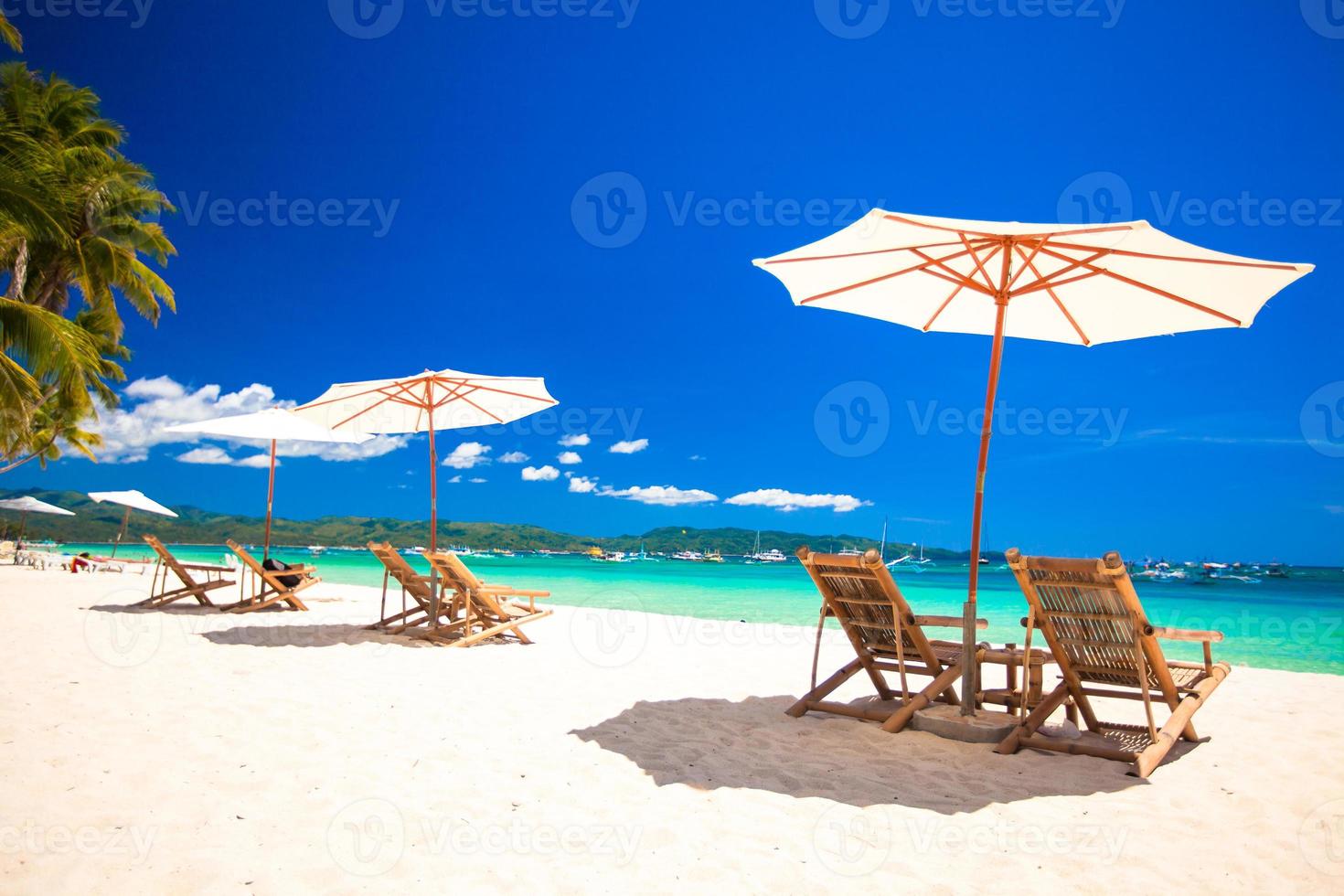 cadeiras de praia e guarda-sóis na exótica praia de areia branca tropical foto