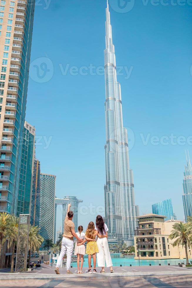 família feliz andando em dubai com o arranha-céu burj khalifa ao fundo. foto