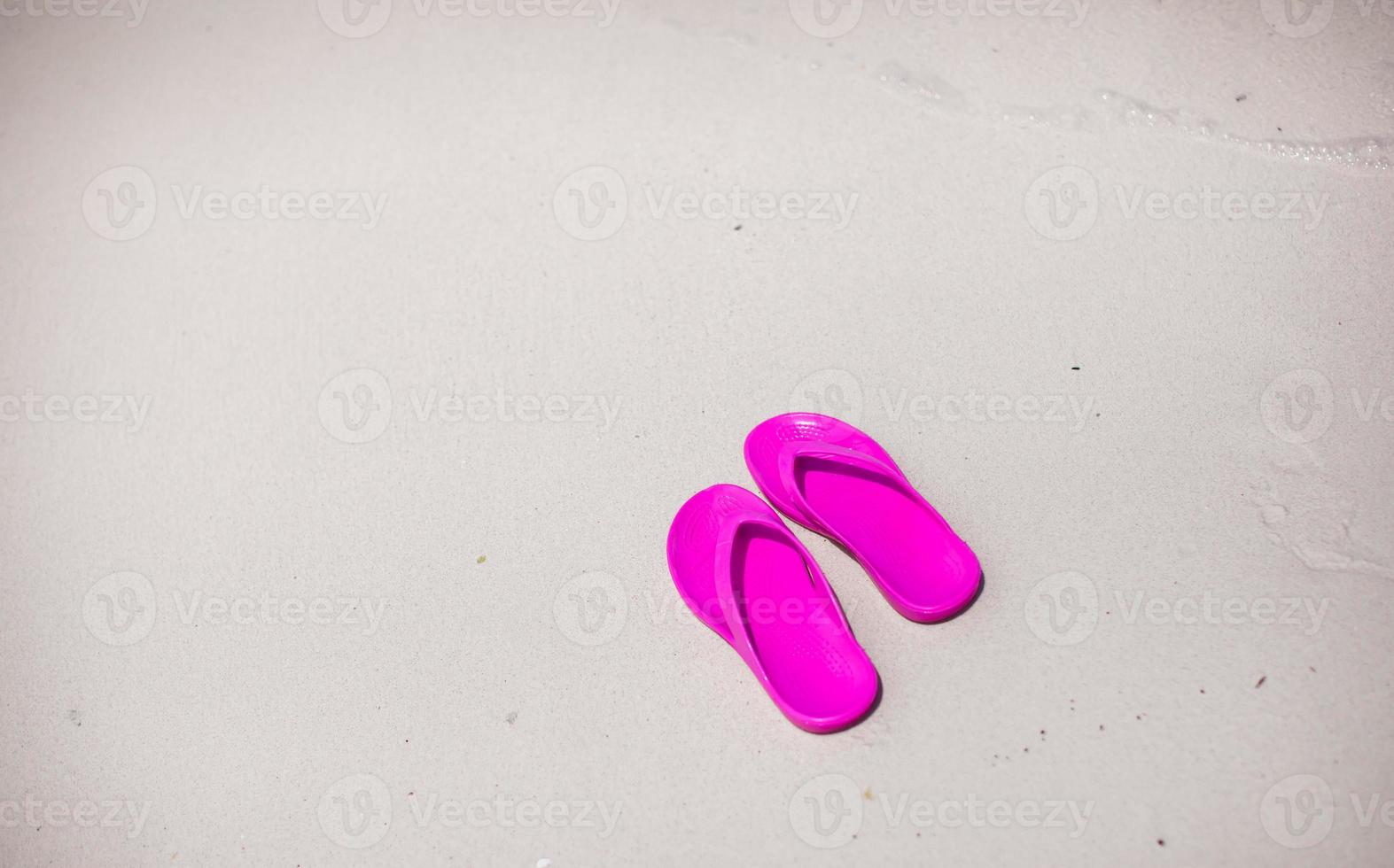 par de chinelos coloridos na praia do mar foto