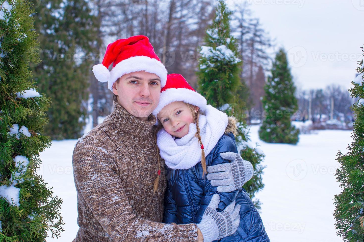 família feliz em chapéus de papai noel com árvore de natal ao ar livre foto