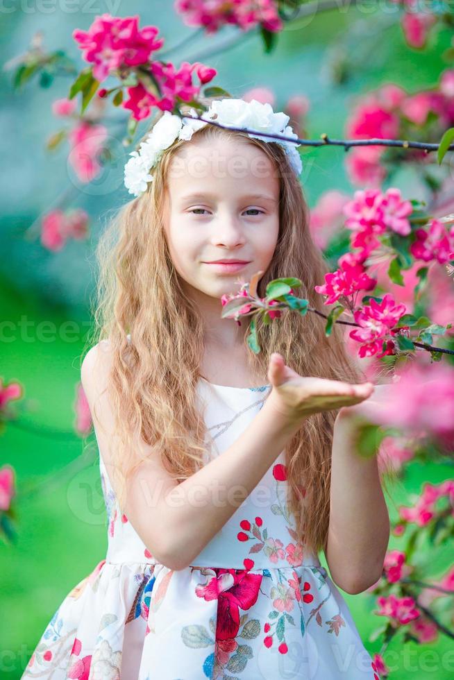 adorável menina apreciando o cheiro em um jardim florido de primavera foto