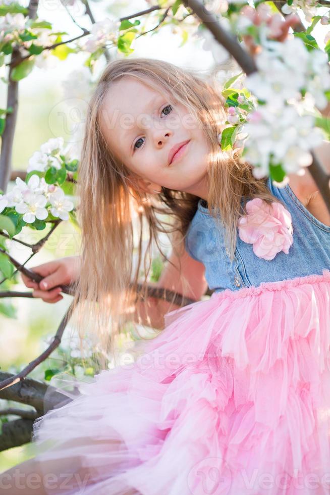 linda garotinha no jardim de macieiras florescendo ao ar livre foto