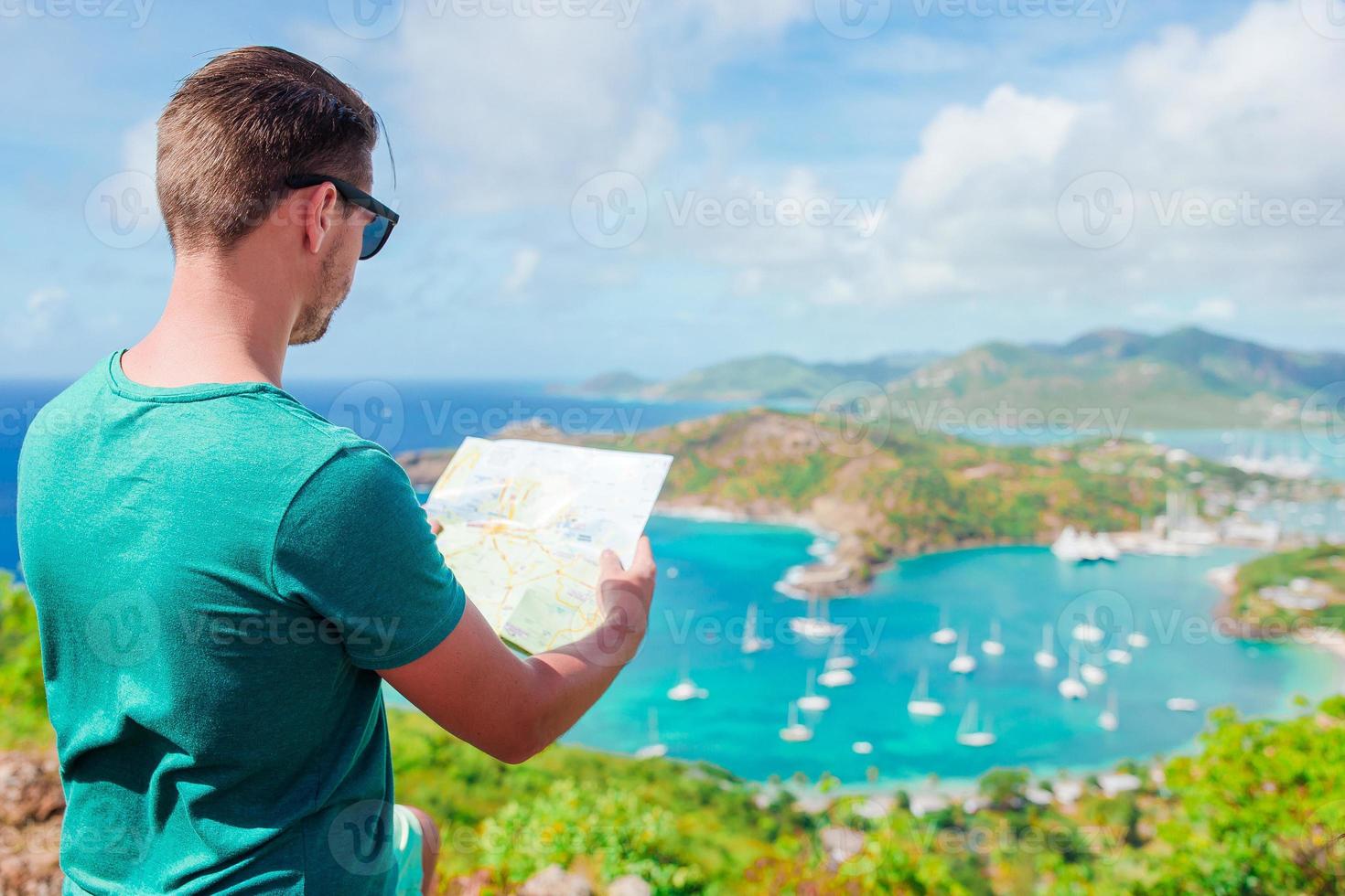 jovem turista com mapa de fundo do porto inglês de shirley heights, antígua, baía paradisíaca na ilha tropical no mar do caribe foto