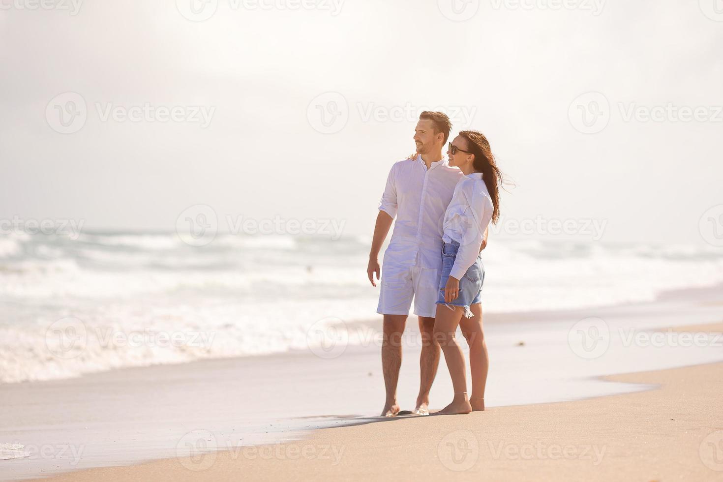 jovem casal apaixonado nas férias de verão na praia. feliz homem e mulher olham para o mar foto