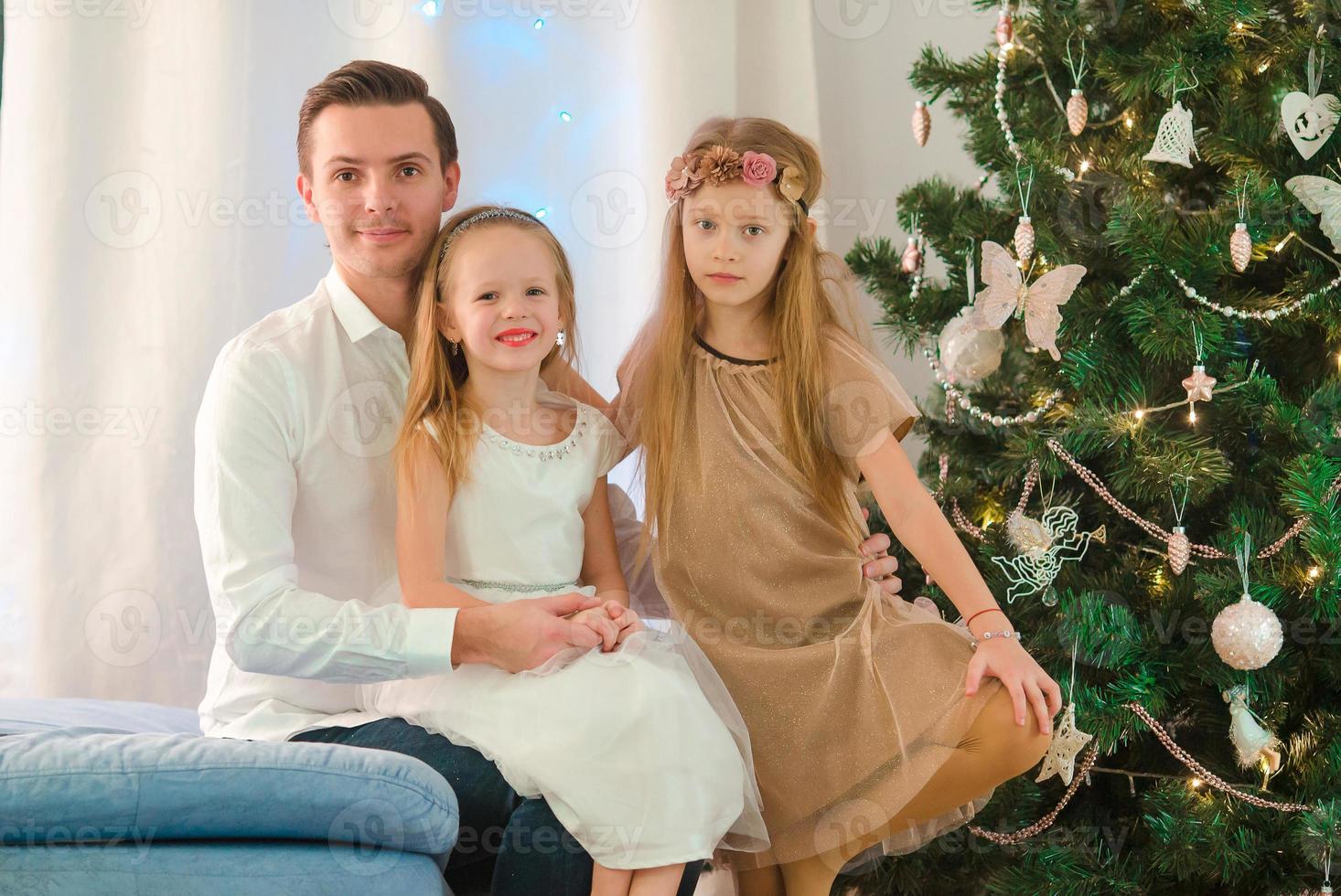 pai feliz com filhos perto da árvore de natal na véspera de natal foto