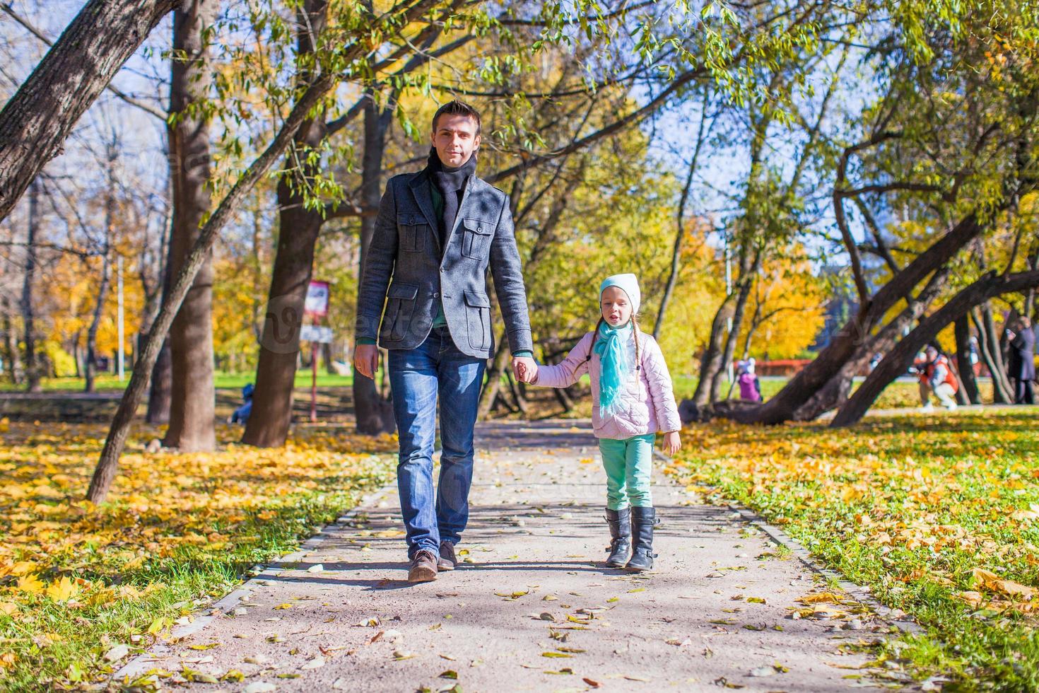 menina adorável com pai feliz andando no parque outono em um dia ensolarado foto