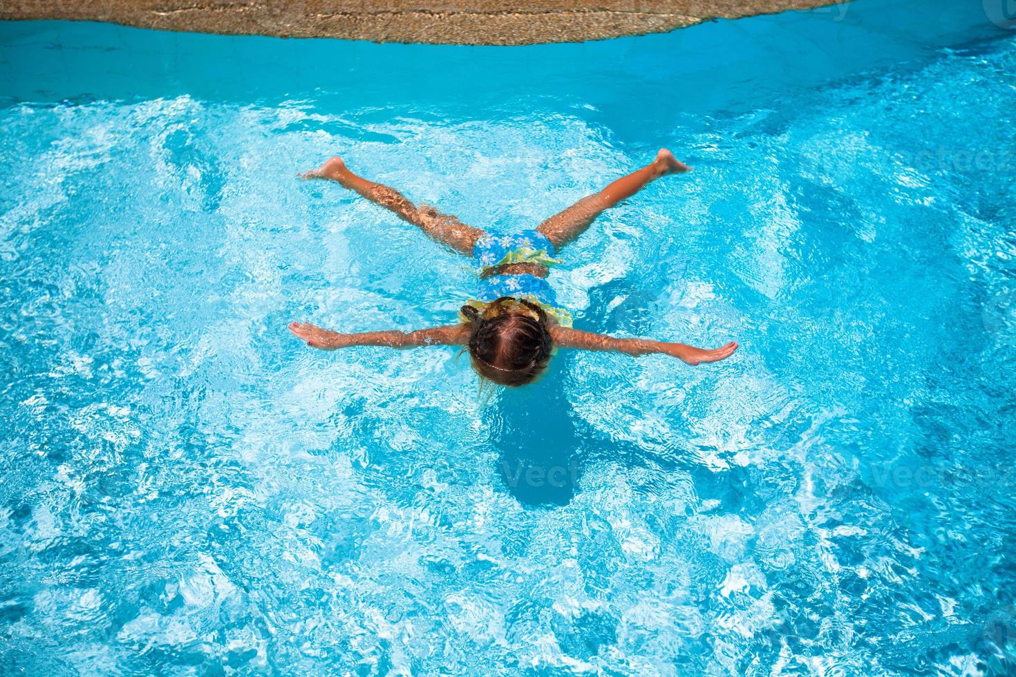 menina bonita e feliz nadando na piscina foto