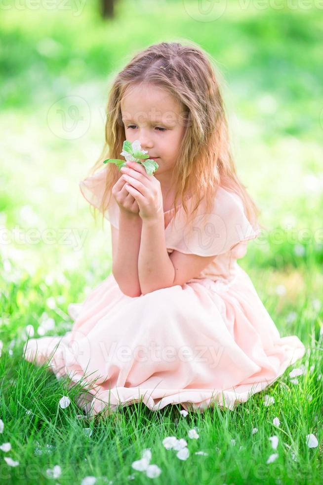 adorável menina apreciando o cheiro em um jardim florido de primavera foto