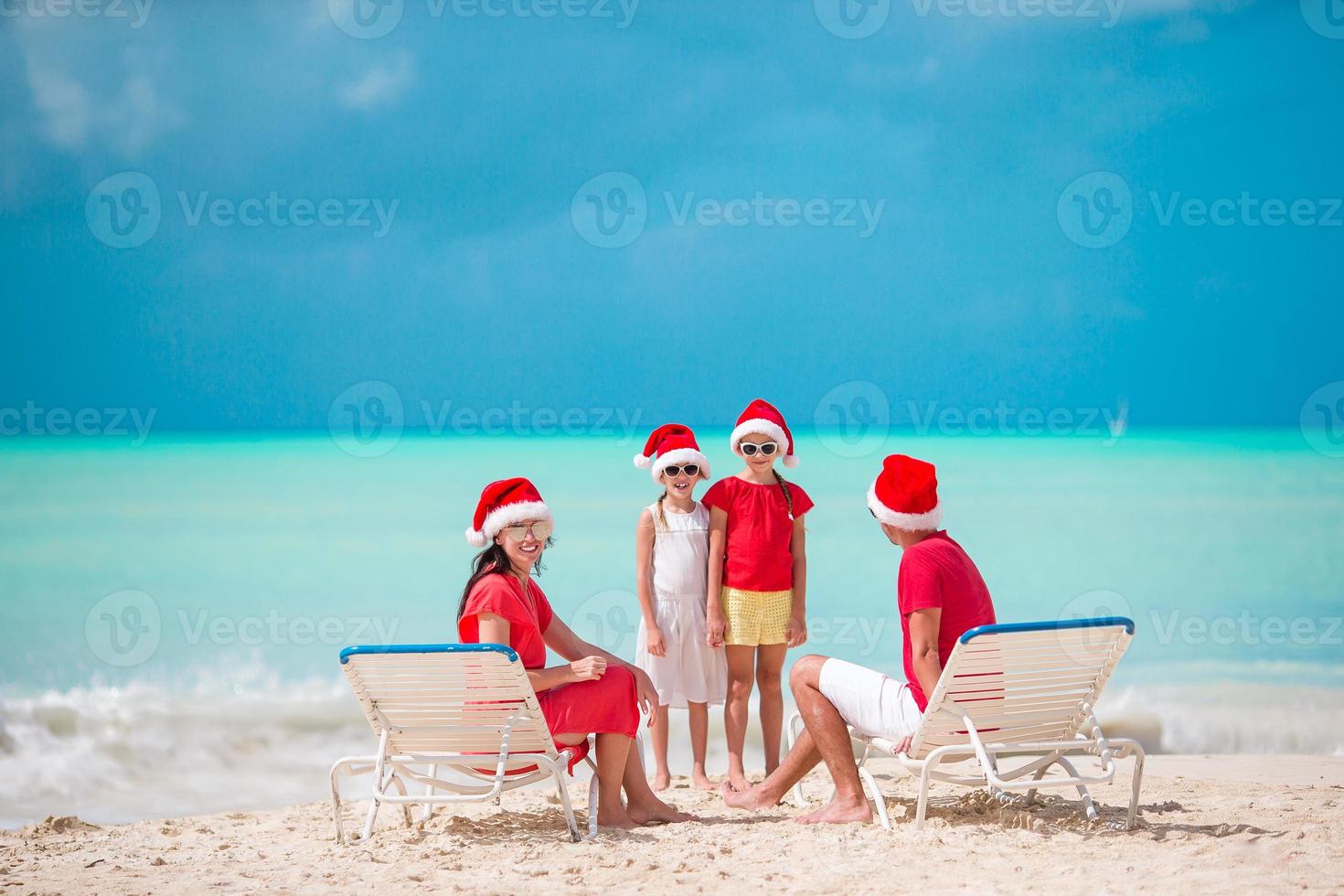 família feliz com dois filhos com chapéu de Papai Noel nas férias de verão foto