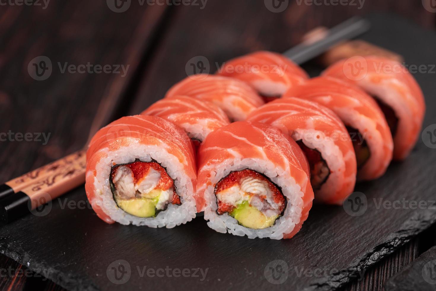 sushi roll maguro com atum, enguia defumada, abacate, queijo philadelphia em close-up de placa preta. cardápio de sushi. comida japonesa. foto