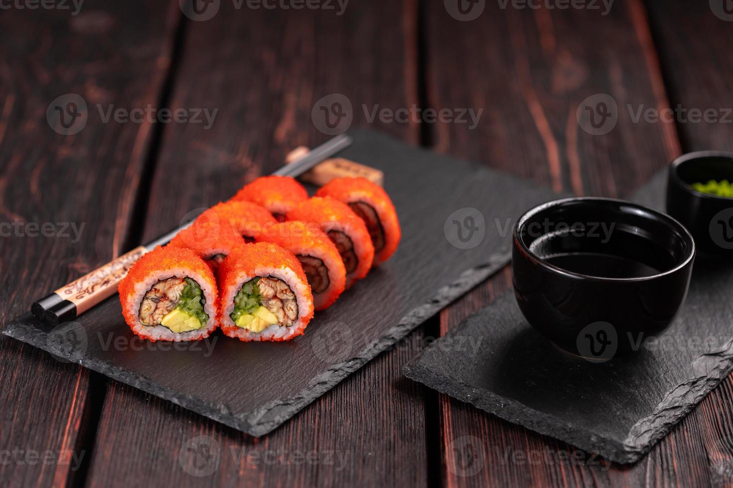 rolo de sushi da Califórnia com enguia, pepino e caviar tobiko servido em close-up de quadro negro - comida japonesa foto