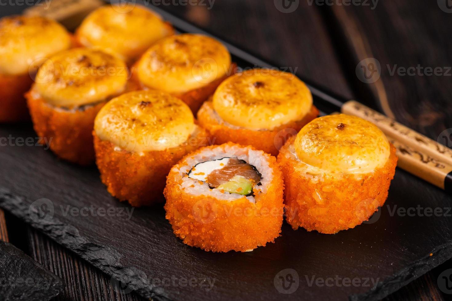 rolo de sushi com caviar de salmão, abacate e tobiko servido em close-up de quadro negro - comida asiática japonesa foto
