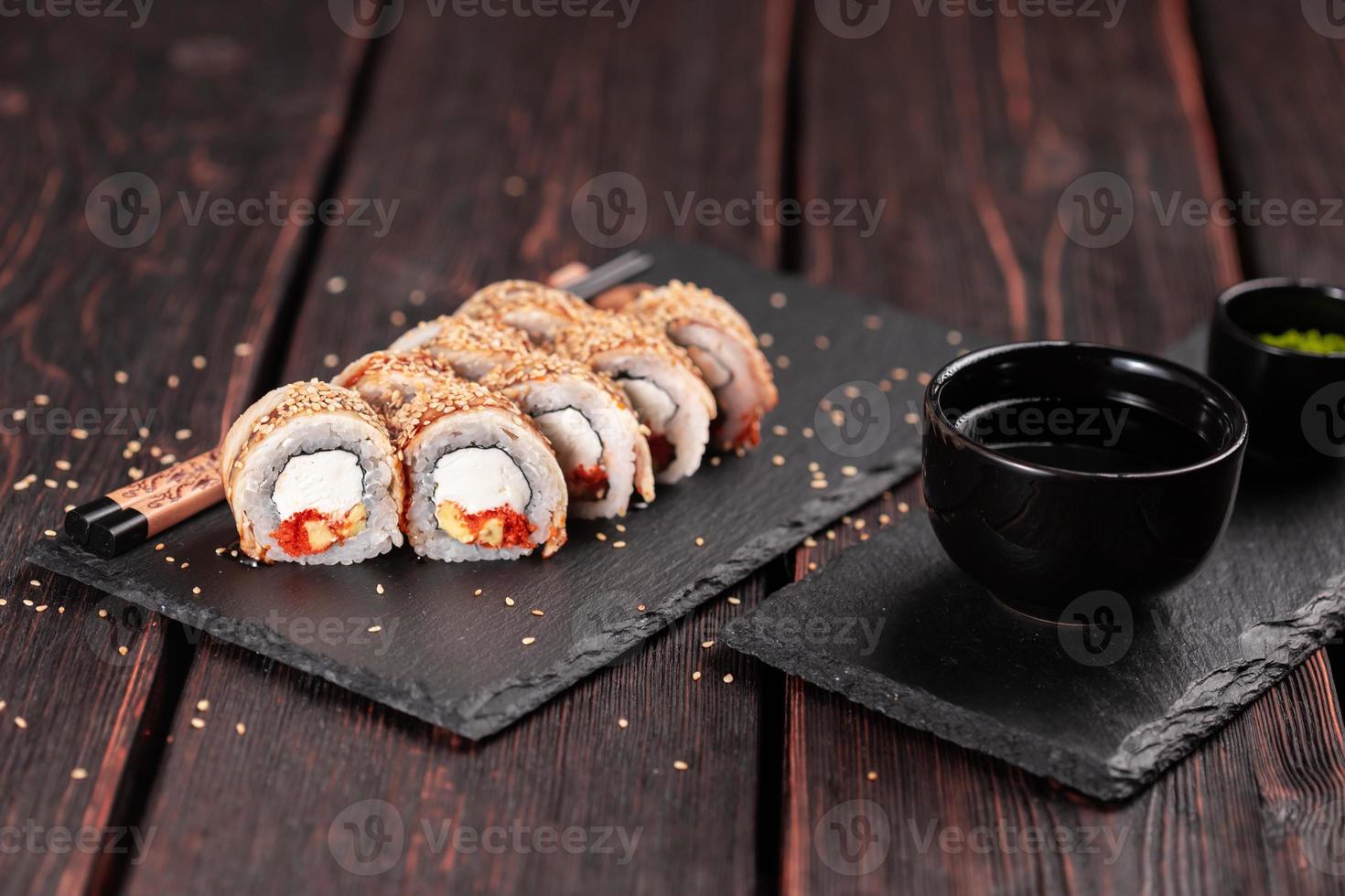 rolo de sushi com enguia defumada e tobiko com close-up de abacate e queijo. tradicional delicioso conjunto de rolo de sushi fresco. cardápio de sushi. restaurante de cozinha japonesa. comida asiática foto