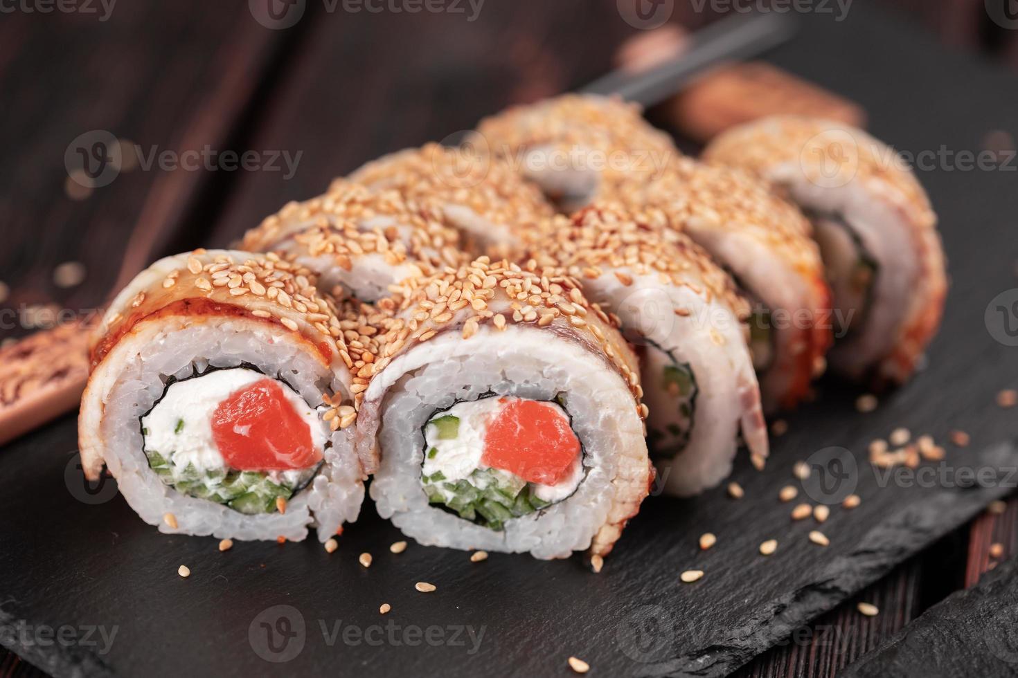 rolo de sushi com enguia defumada e salmão com close-up de pepino e queijo. tradicional delicioso conjunto de rolo de sushi fresco. cardápio de sushi. restaurante de cozinha japonesa. comida asiática foto