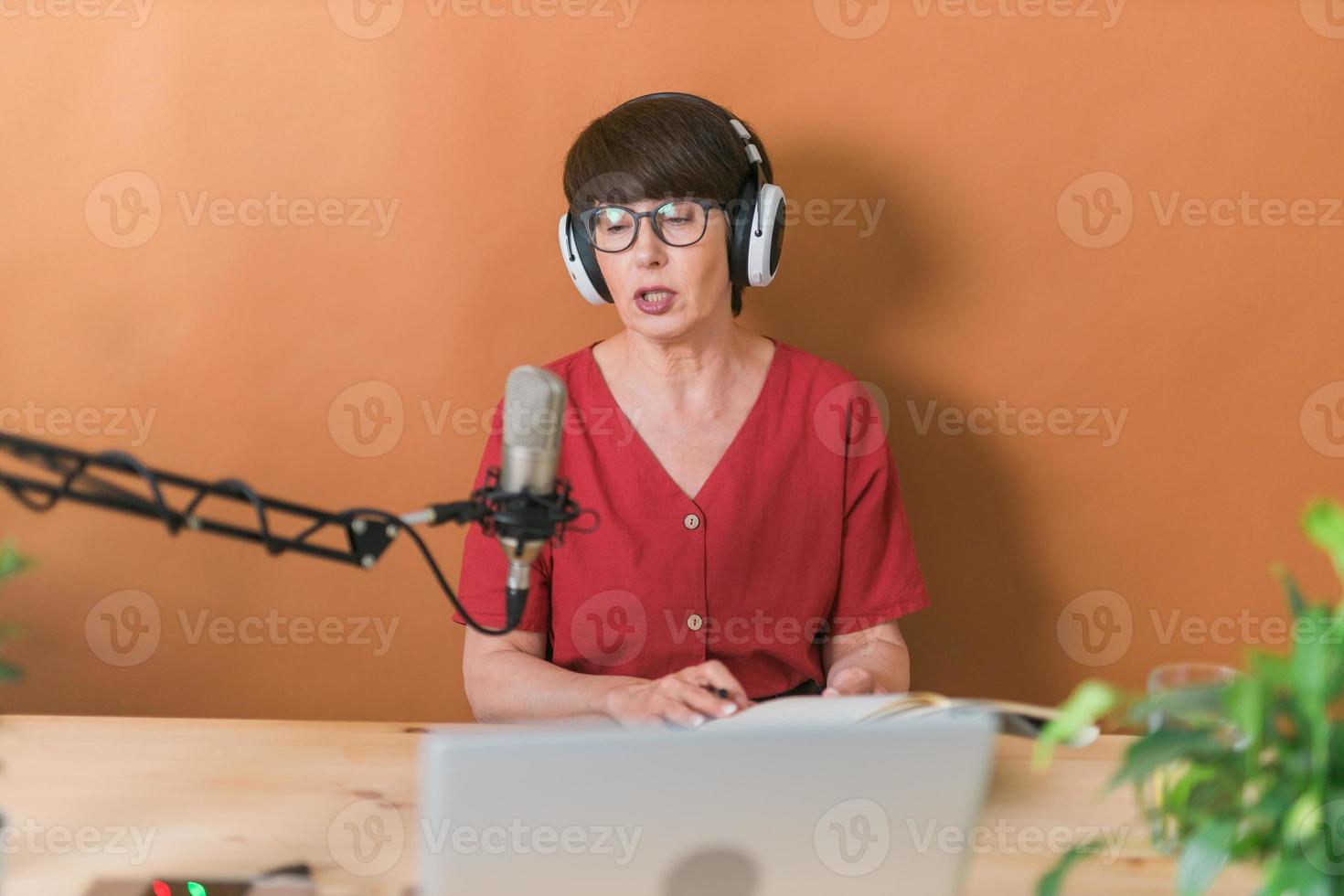 retrato de mulher madura usando fones de ouvido e falando na estação de rádio online - conceito de podcast e transmissão foto