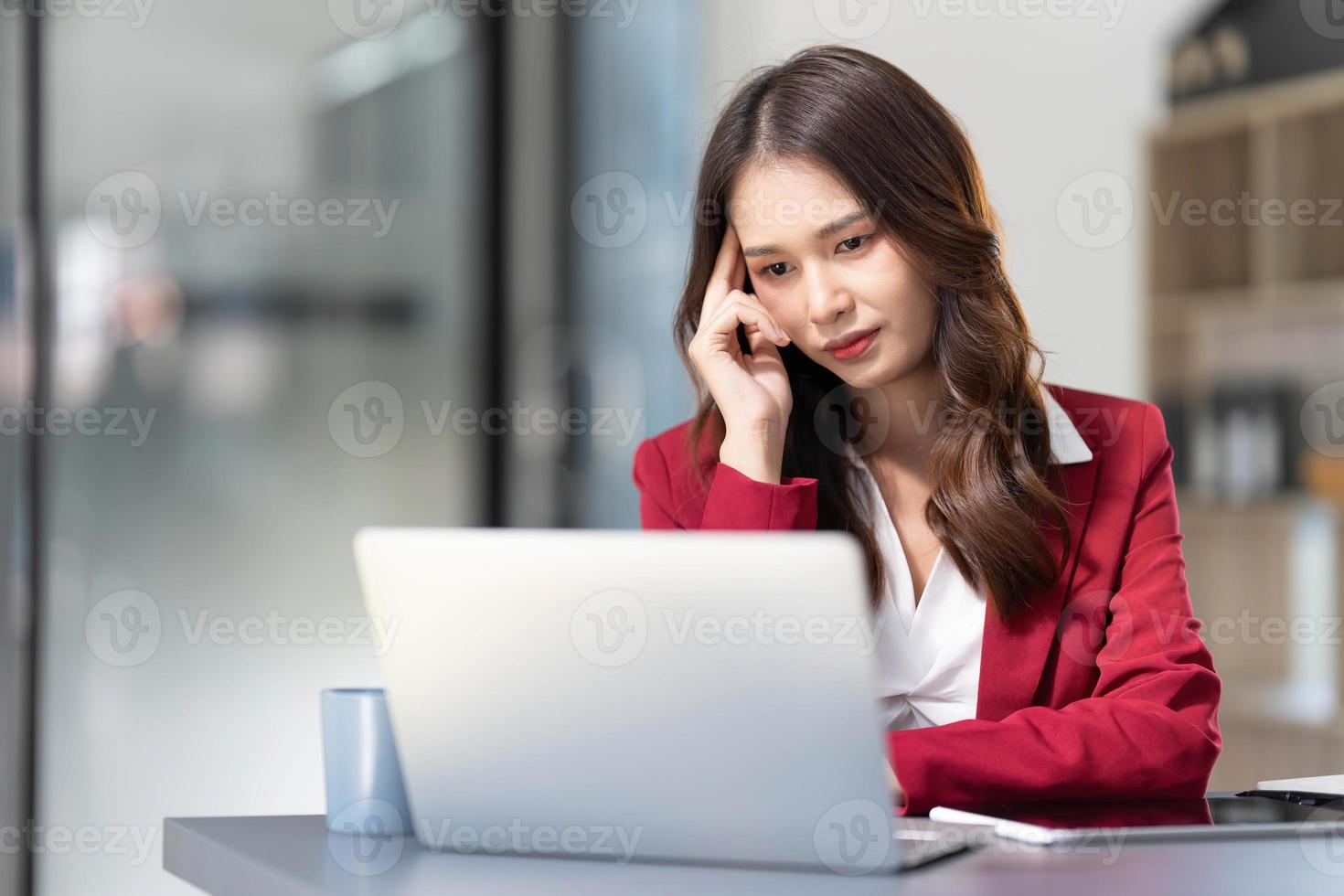 mulher asiática pensando muito preocupada com a solução de problemas on-line olhando para a tela do laptop, preocupada empresária asiática séria focada em resolver tarefa difícil de computador de trabalho foto