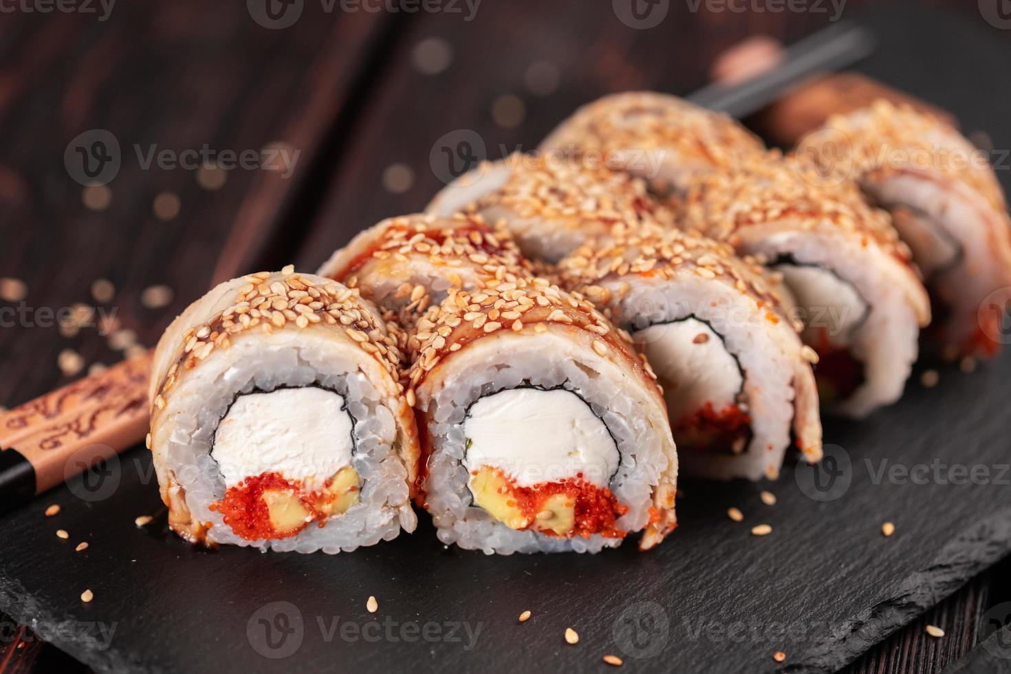 rolo de sushi com enguia defumada e tobiko com close-up de abacate e queijo. tradicional delicioso conjunto de rolo de sushi fresco. cardápio de sushi. restaurante de cozinha japonesa. comida asiática foto