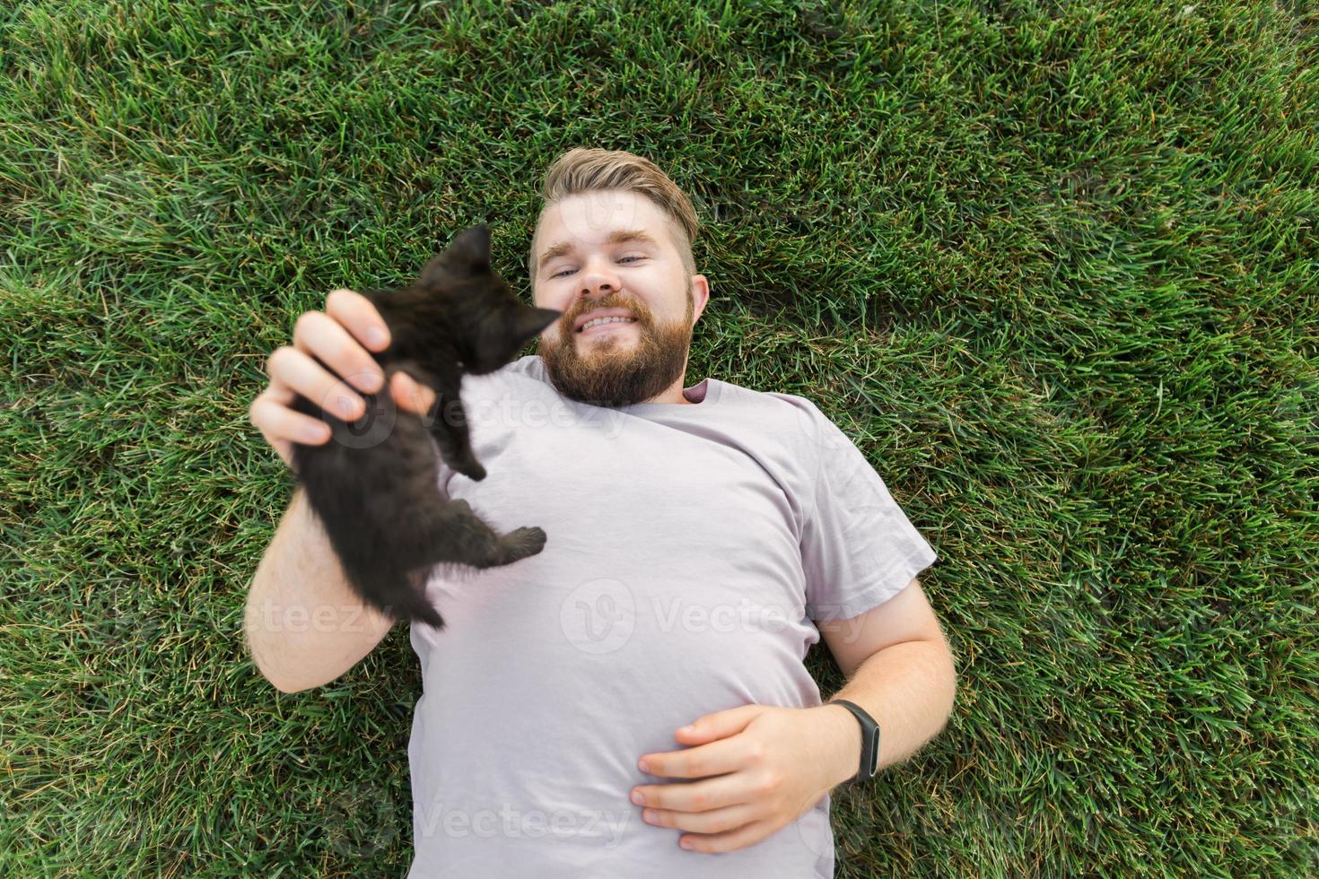 homem com gatinho deitado e brincando na grama - animais de amor de amizade e conceito de dono de animal de estimação foto