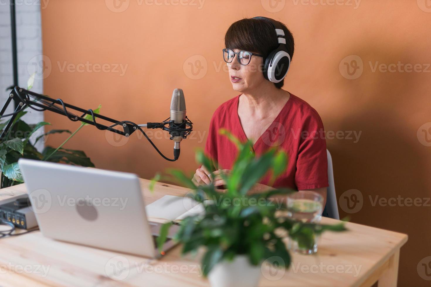 apresentadora de rádio feminina de meia-idade falando no microfone e lendo notícias - conceito on-line de transmissão de rádio foto