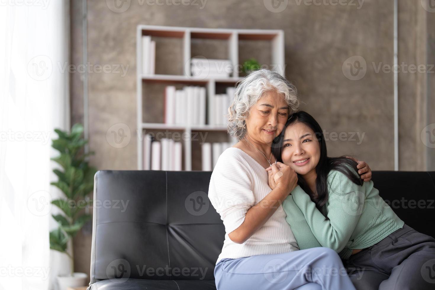 filha adulta amorosa abraçando a mãe mais velha, de pé atrás do sofá em casa, família desfrutando de um momento de ternura juntos, jovem e mãe madura ou avó olhando uma para a outra, duas gerações foto