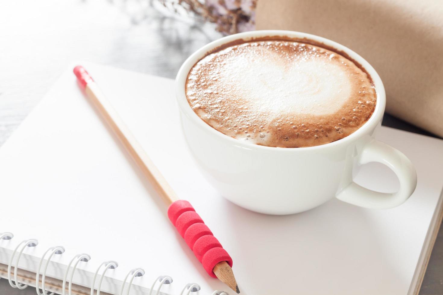 café com leite e lápis em um caderno foto