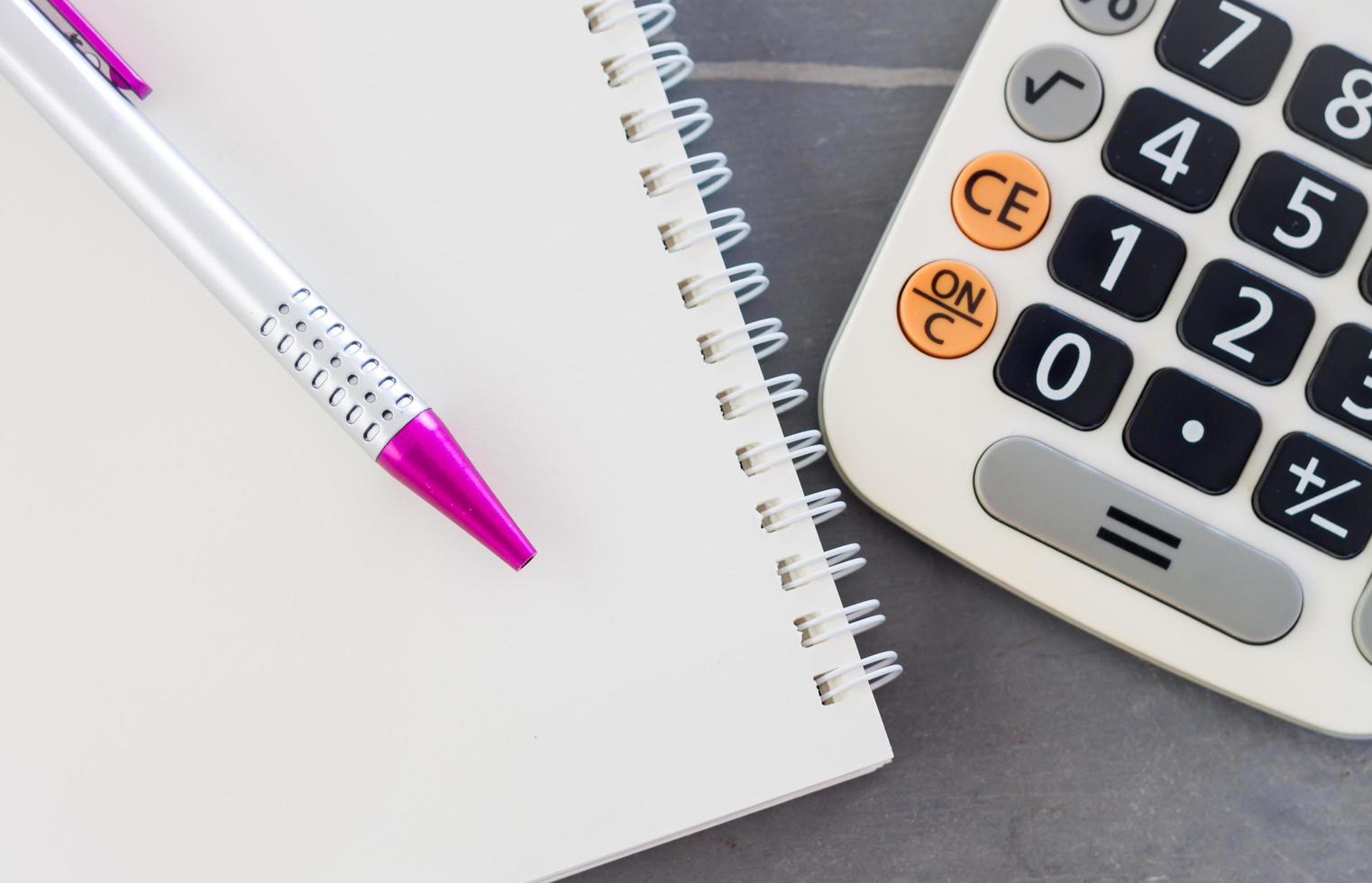 close-up de uma caneta, caderno e uma calculadora foto