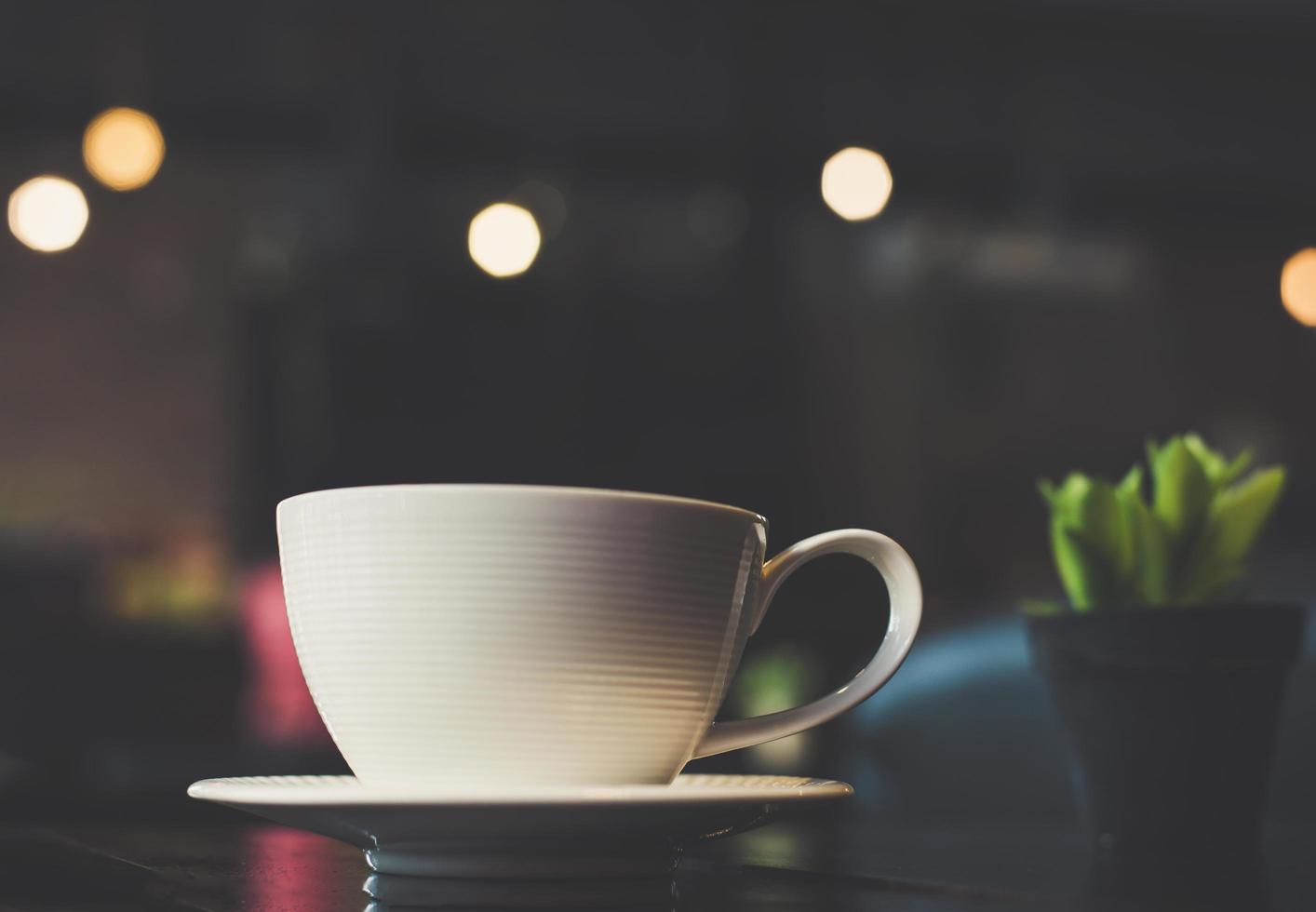 xícara de café com cacto na mesa de madeira foto