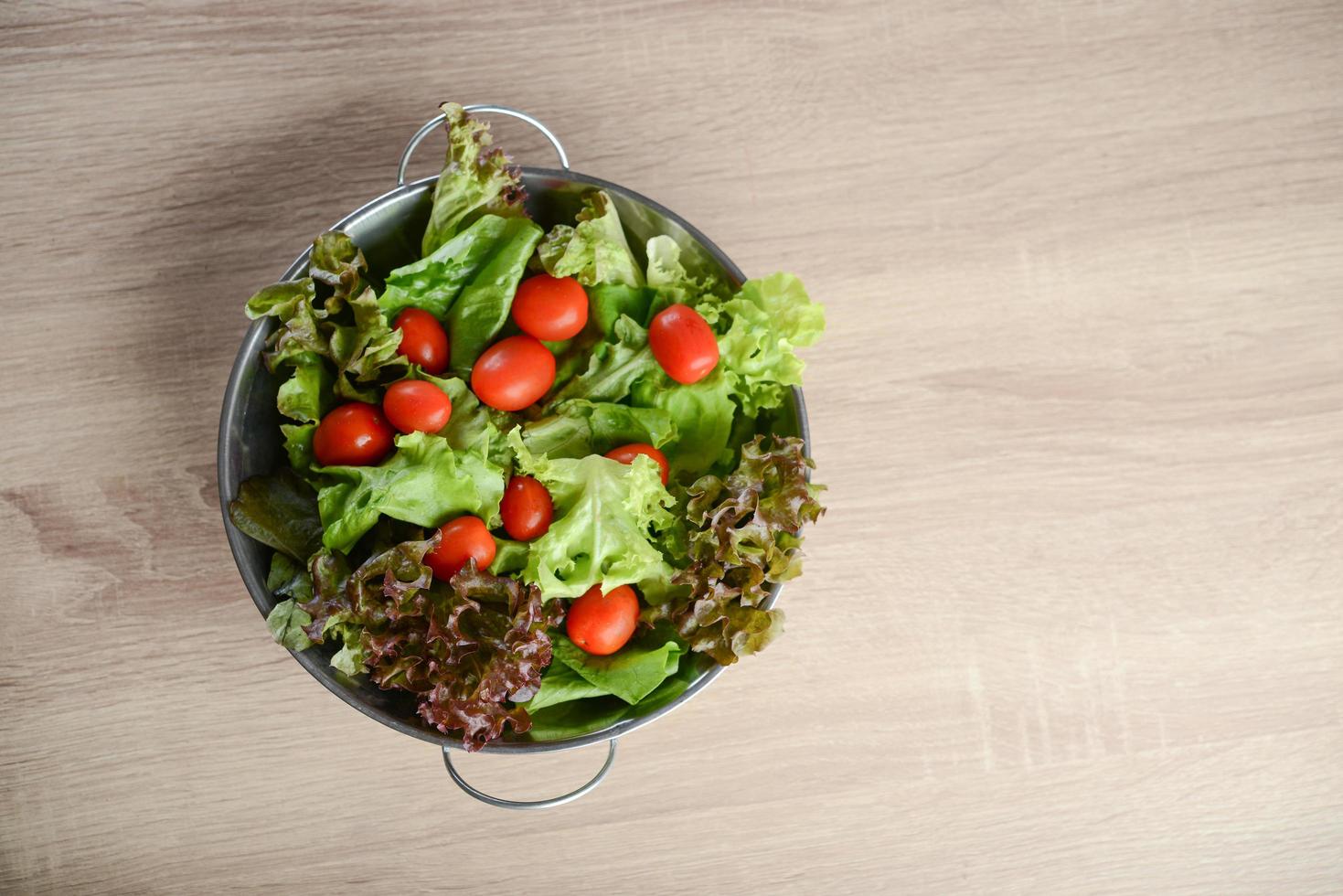 Salada fresca com legumes e verduras na mesa de madeira foto
