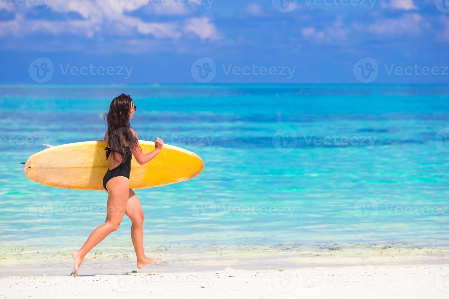 mulher de surf bem torneada feliz na praia branca com prancha de surf amarela foto