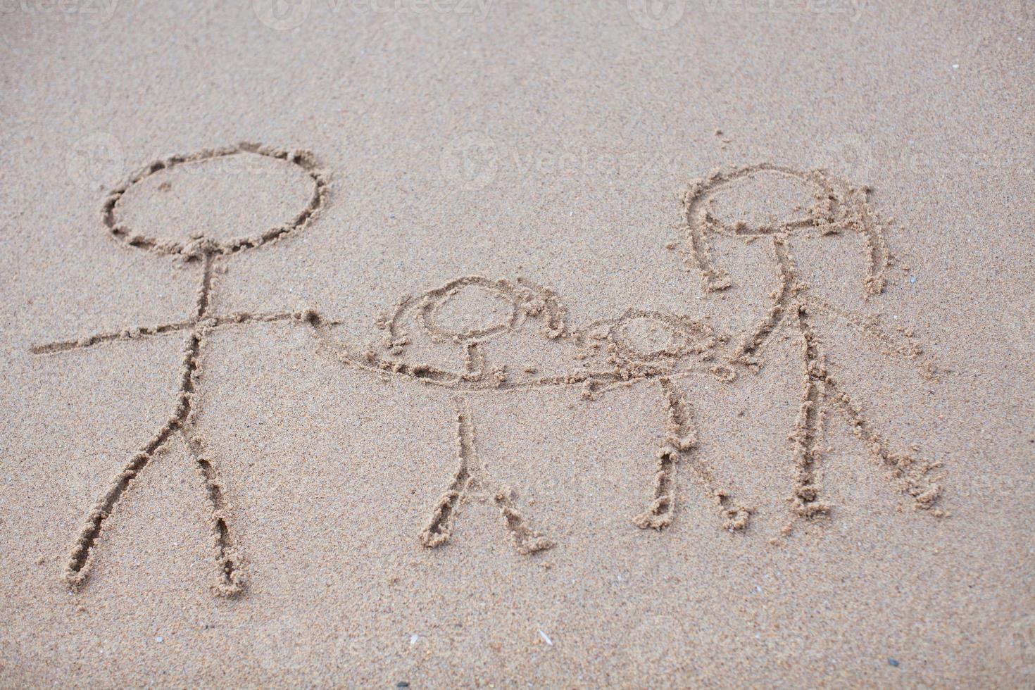 família de quatro pessoas desenhando na praia foto