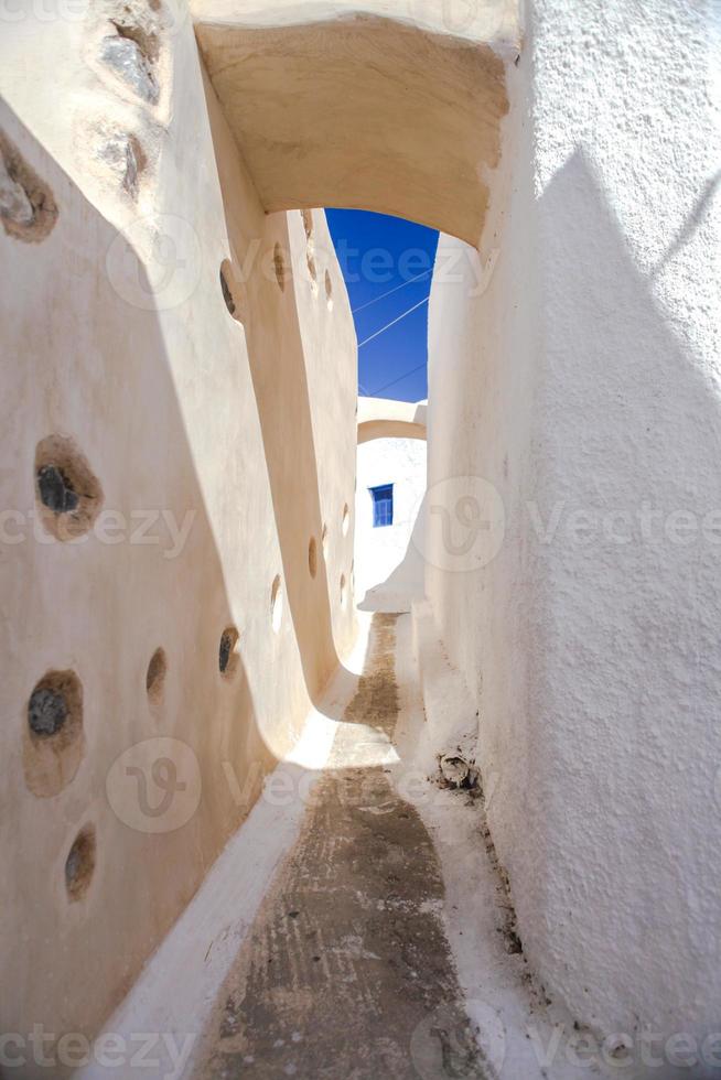 bela rua pavimentada com a velha casa branca tradicional em emporio santorini, grécia foto