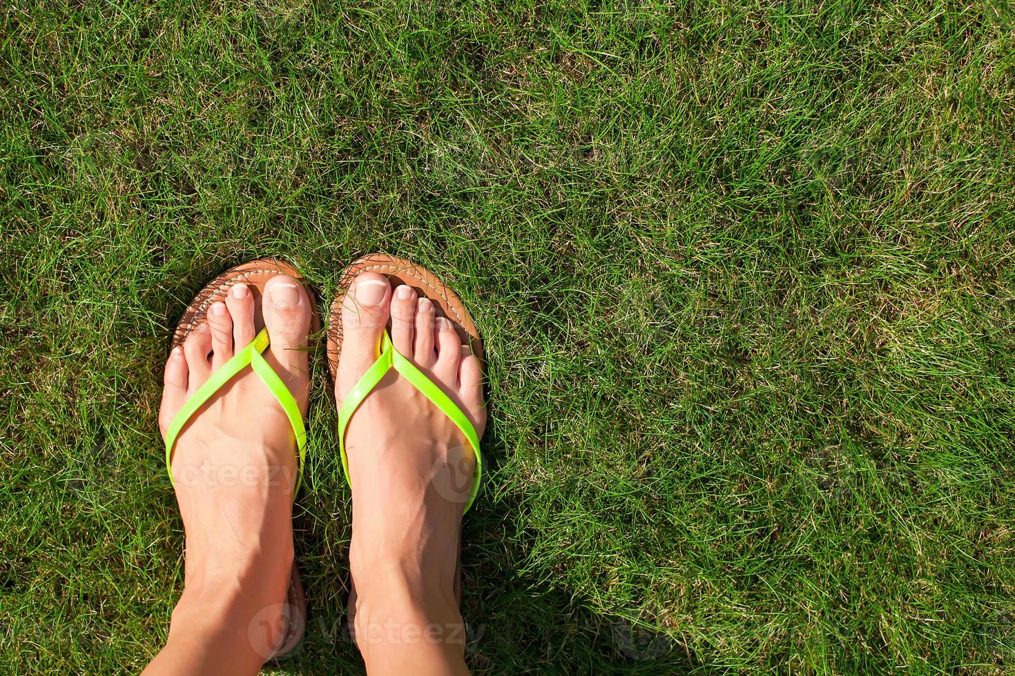 closeup de chinelos brilhantes e pernas na grama verde foto