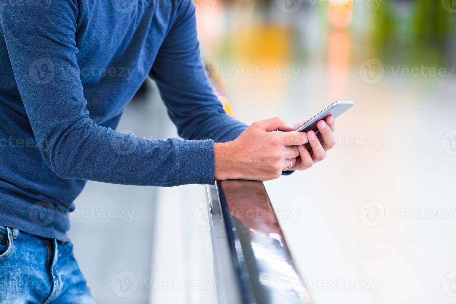 homem com mochila segurando celular no aeroporto esperando o voo foto