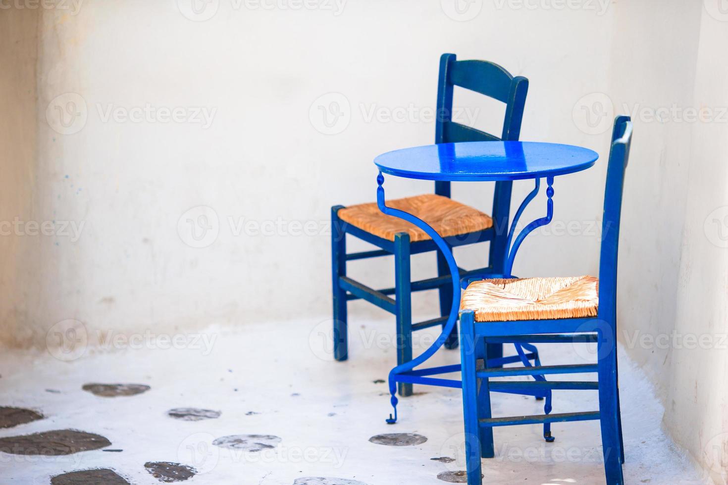 duas cadeiras azuis em uma rua da típica aldeia tradicional grega na ilha de mykonos, grécia, europa foto