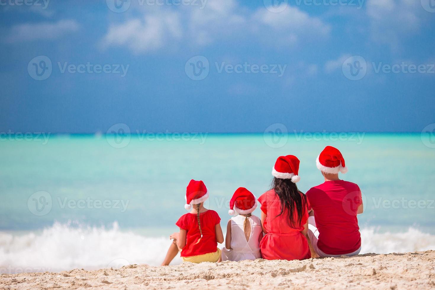família feliz com dois filhos com chapéu de Papai Noel nas férias de verão foto