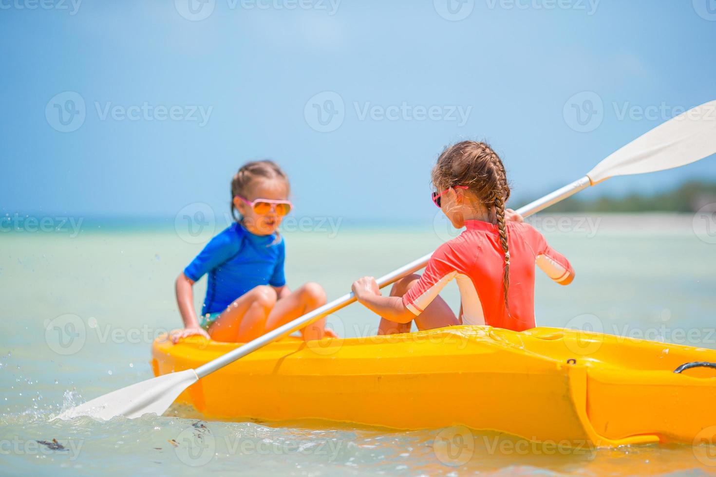 meninas adoráveis, desfrutando de caiaque no caiaque amarelo foto