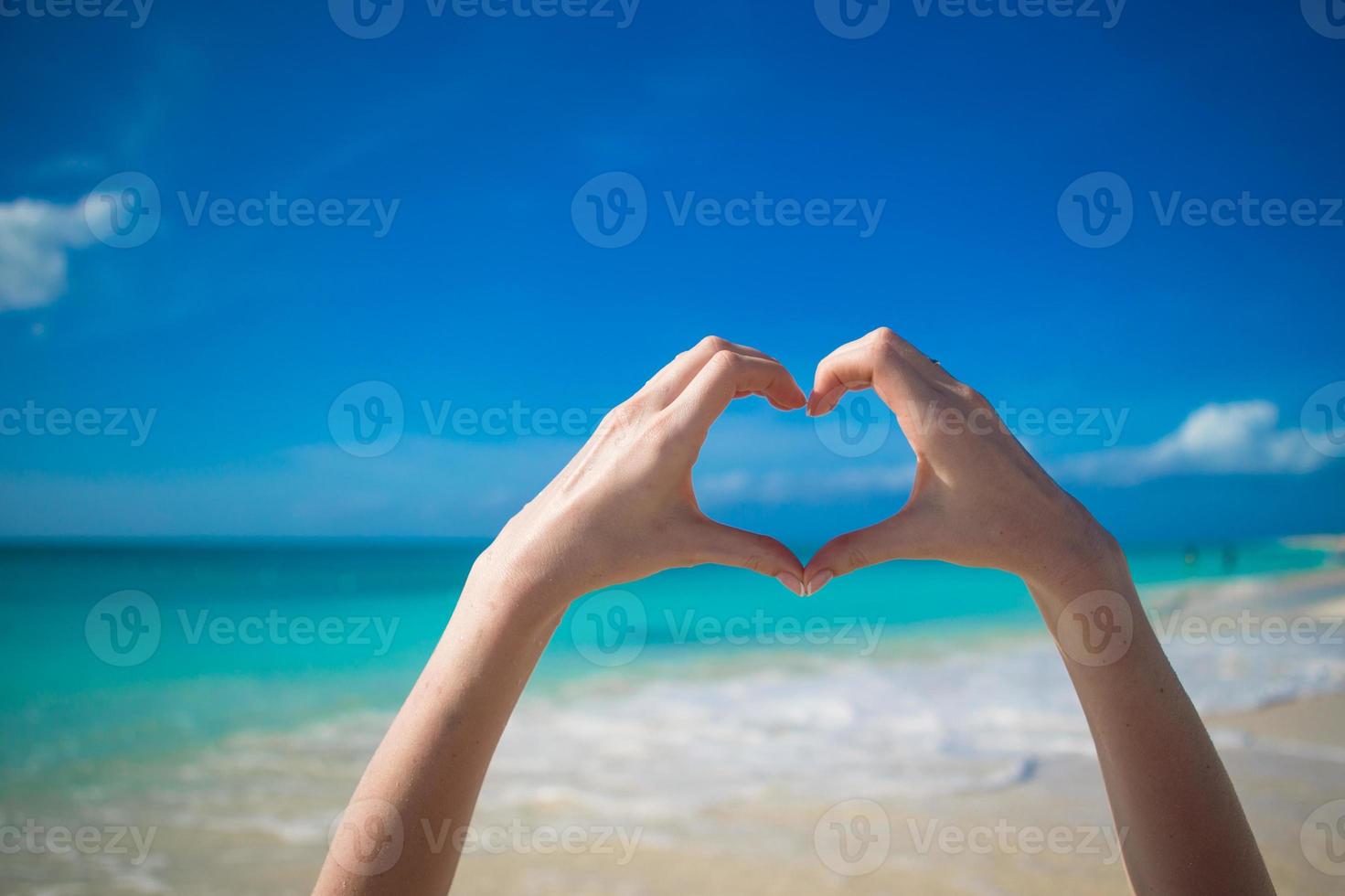 close-up do coração feito por mãos femininas fundo do oceano turquesa foto